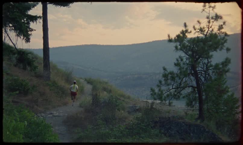 Person running up a mountain trail at sunrise