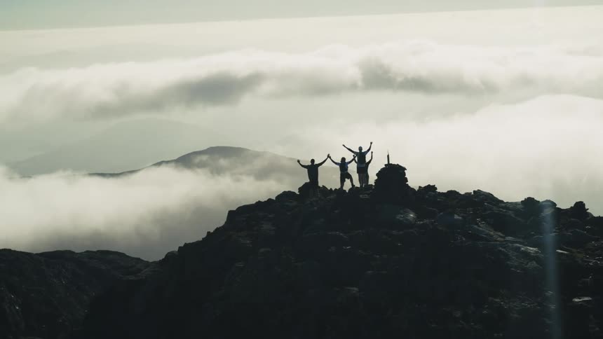 Aerial view of people on a rocky mountain peak above cloud level