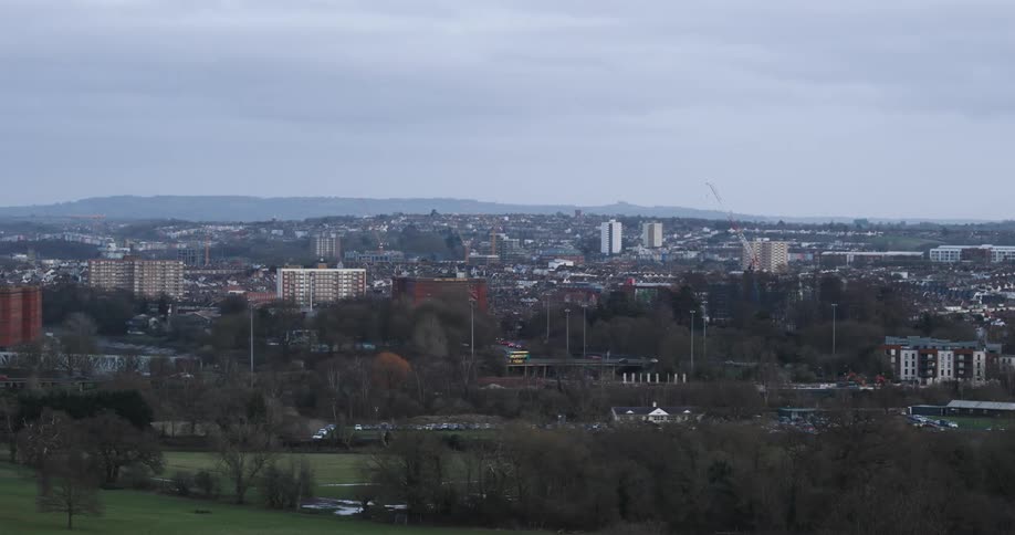 An aerial view of a city with lowrise buildings and a huge park with trees in front