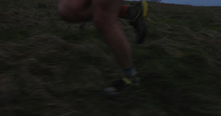 A closeup of a persons lower legs running against a grassy terrain
