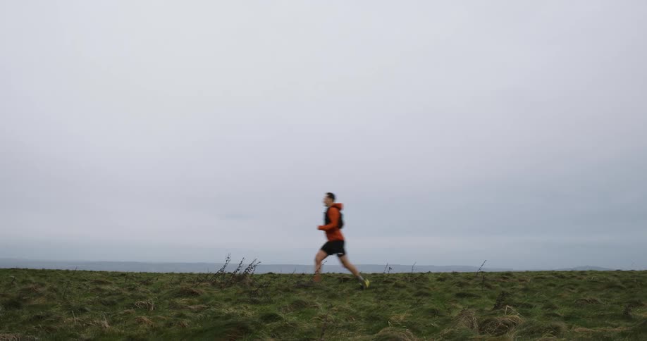Man running in a field on a cloudy day