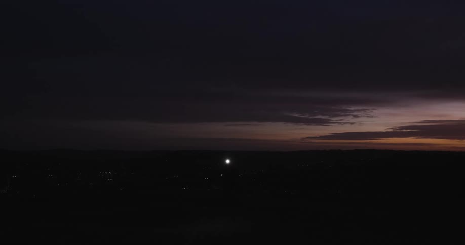 Silhouette of a person against a twilight sky running with a flashlight on his head