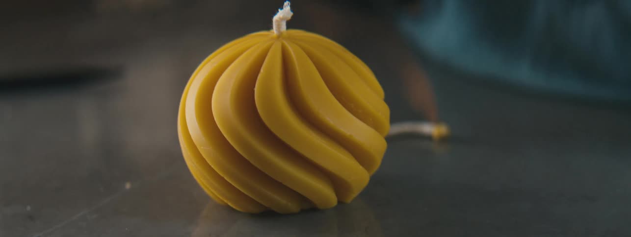 Pair of hands of a craftswoman working on a yellow spherical object with tweezers