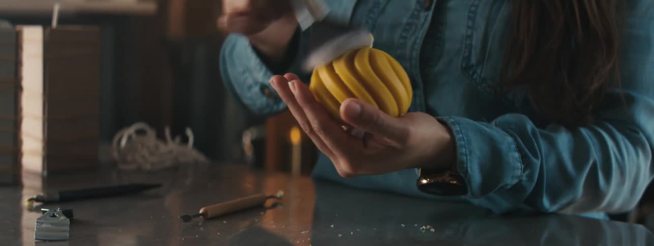 A woman brushes a yellow round object in a room