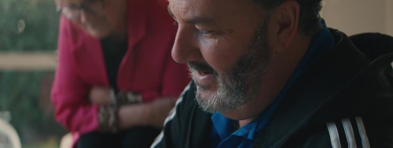 A man and an older woman bent slightly forward while smiling then the man turns and looks at the woman
