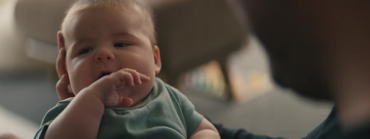 A man holds a baby and makes the baby laugh