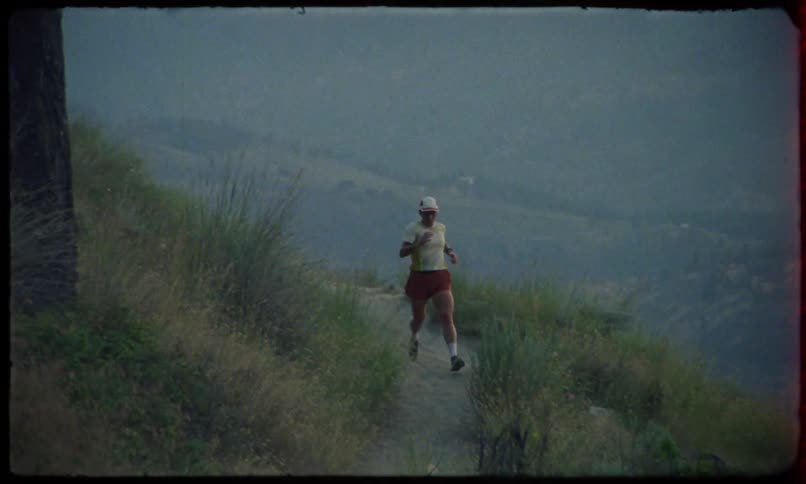 A woman is running on a dirt path amidst grass vegetation