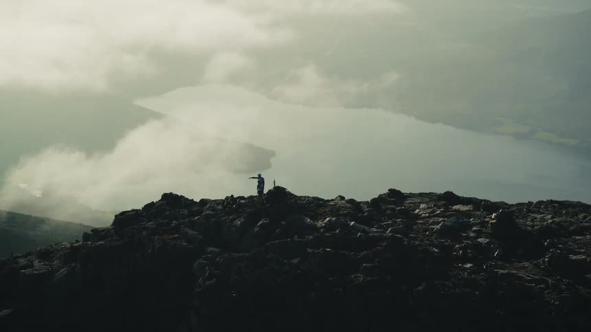 An adult and a child at the top of a mountain as the adult points to the view around them