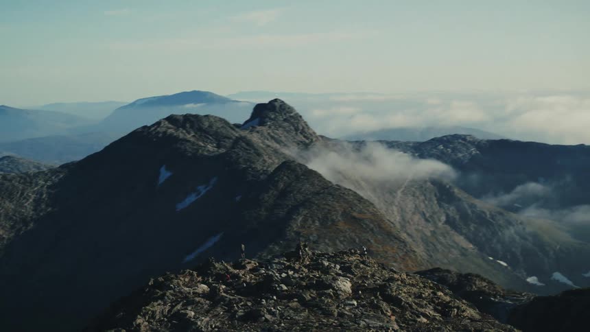 Aerial panorama of a mountain valley with people on a peak