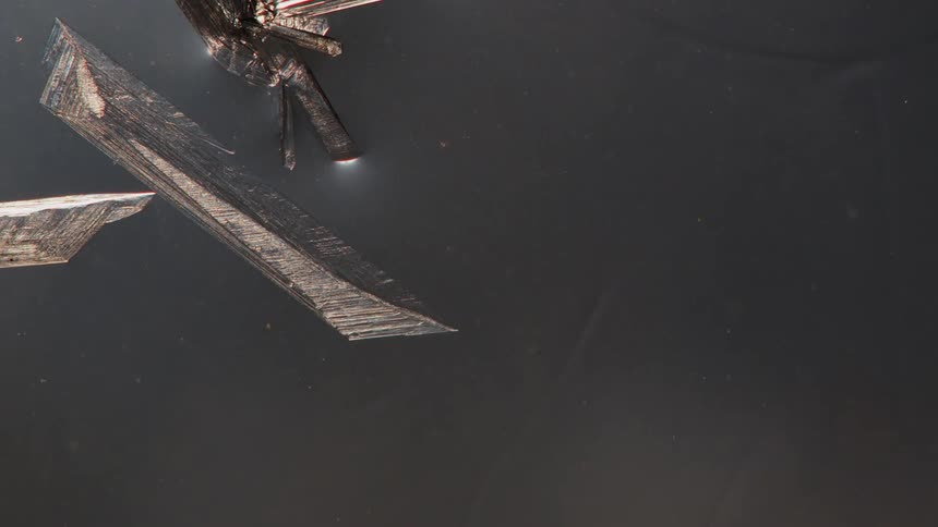 Close up of clear crystals growing on a liquid