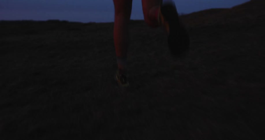 A person runs across a grassy plain at dusk