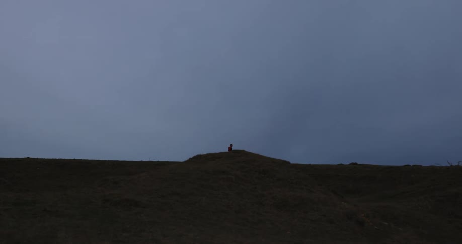 A person runs across a ridge on a grassy plain