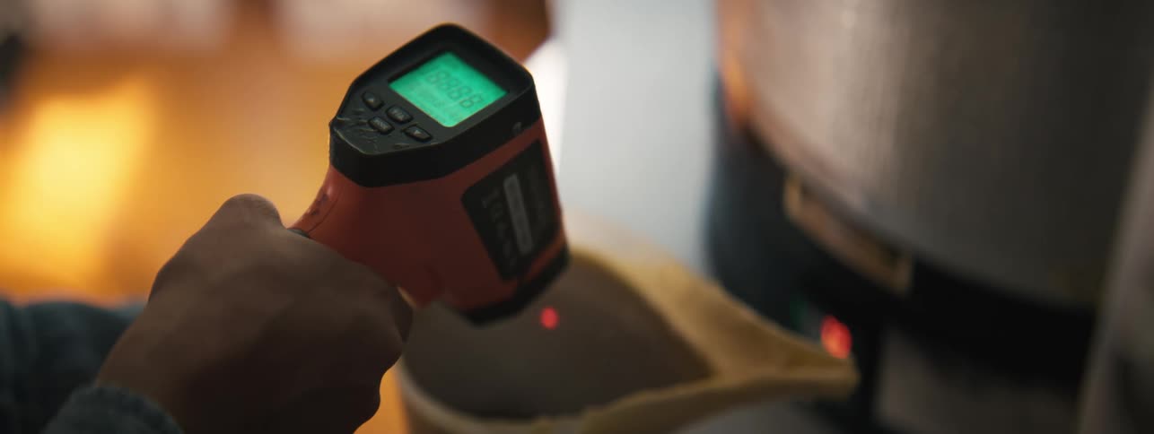 Person with digital thermometer checking the temperature of a liquid