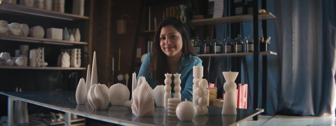 Young man and woman smiling in front of seashell artwork arranged on a table