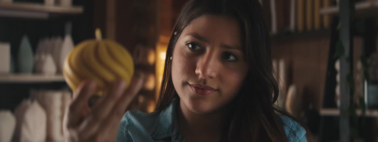 Portrait of a woman with a happy and stinky facial expression looking at a yellow round candle