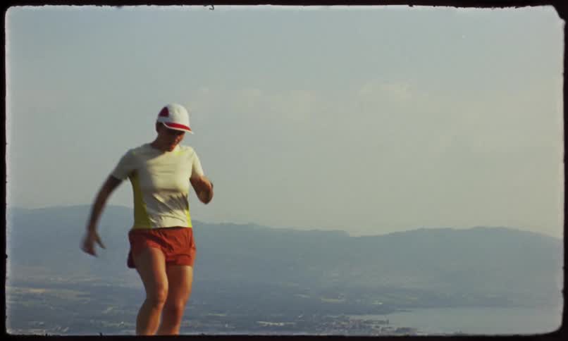 A running woman reaches the top of a hill captured on vintage film