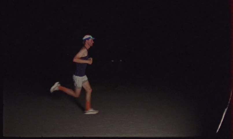 A man is running in the dirt at night