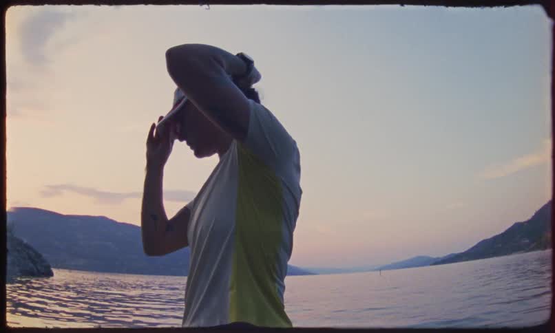 Man by the sea twisting his cap and putting it on his head