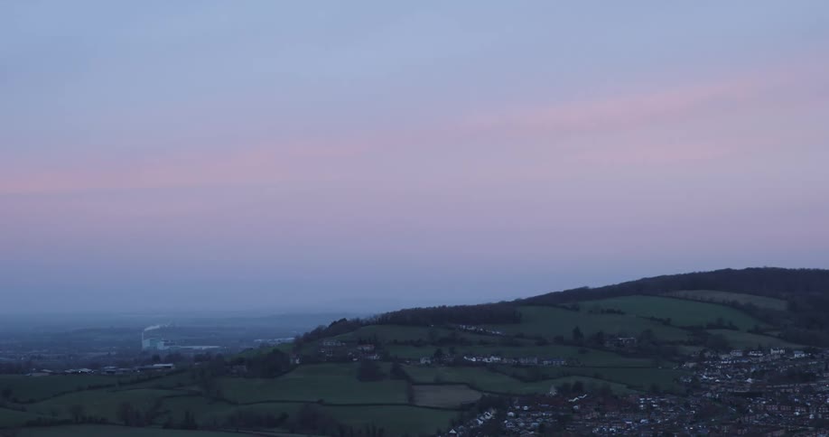 A rural community sits on the side of a hill near a construction crane