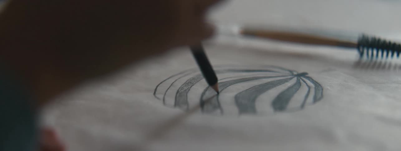 Womans hand with a black pencil illustrating a drawing