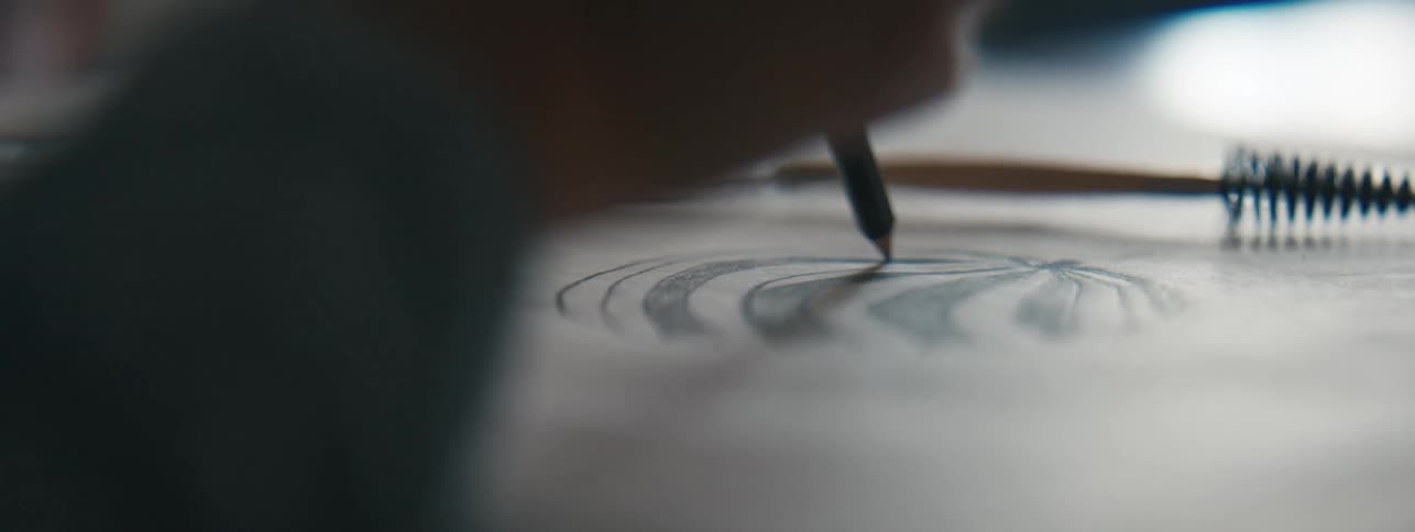 A closeup view of a persons hand holding a pencil and sketching on paper