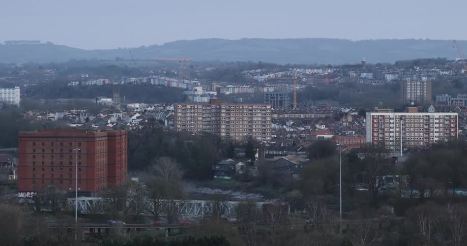 A sprawling cityscape with apartment buildings and a bridge surrounded by trees