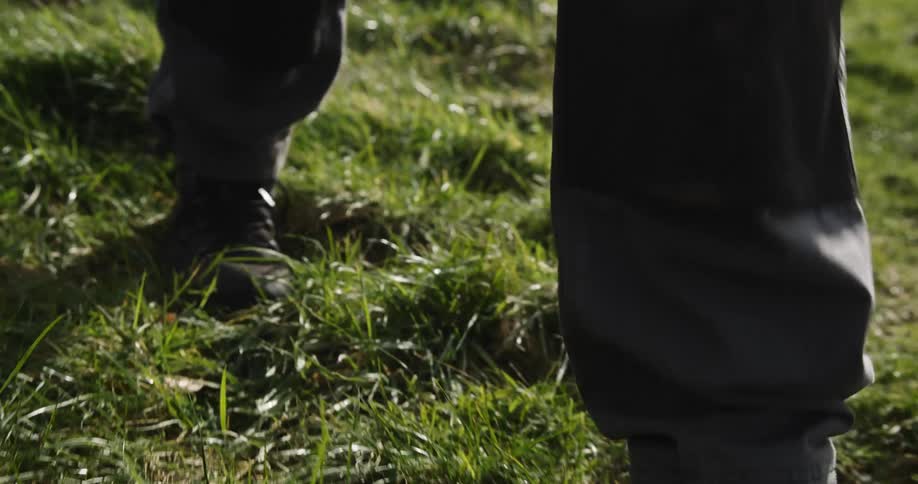 Close up of a persons feet in boots walking on grass