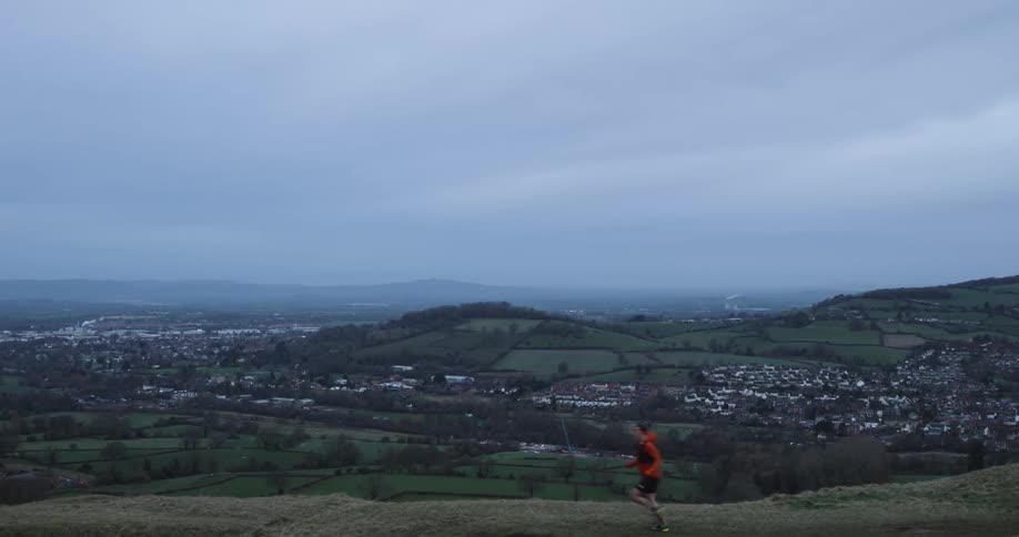 Person running on a hill with a city in the background