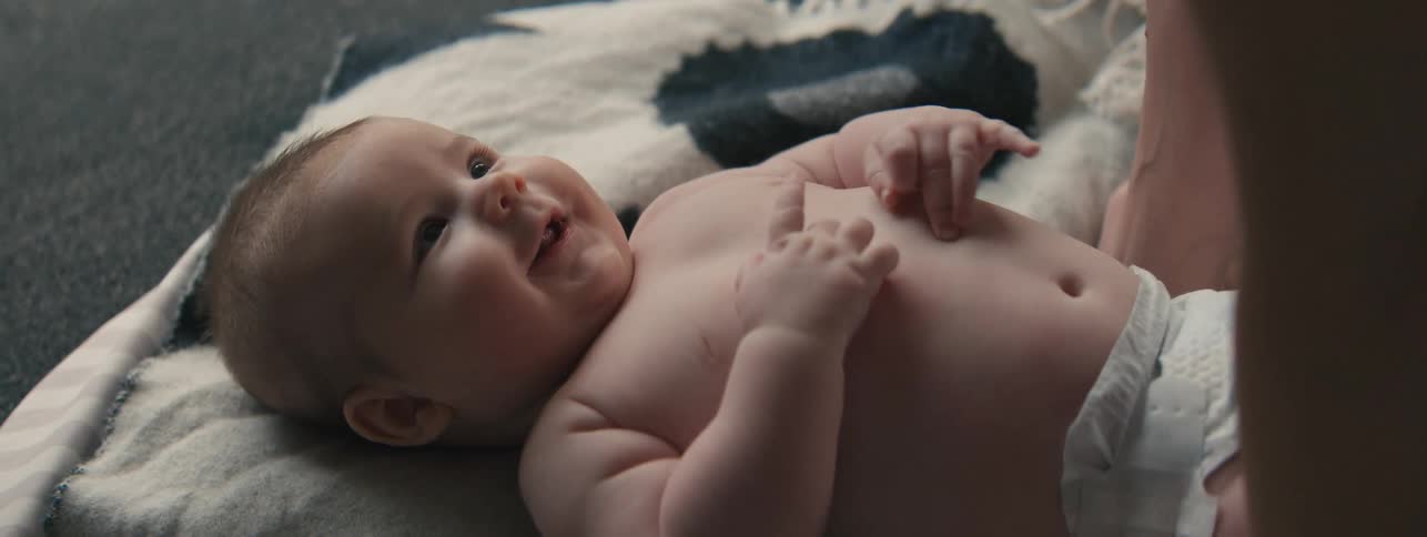 Portrait of a baby being cuddled while lying on a blanket on the floor