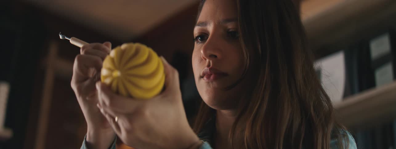 A young woman sculpting grooves into a yellow ball