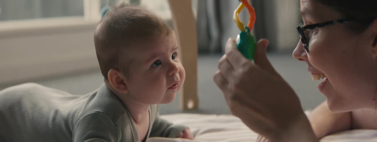 Hand with a toy in hand playing with her baby son