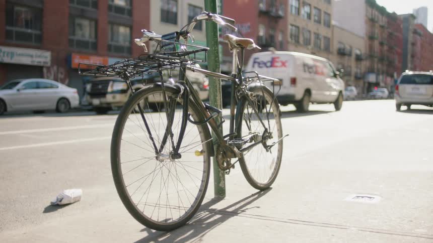 Traffic passes a bike leaning against a pole