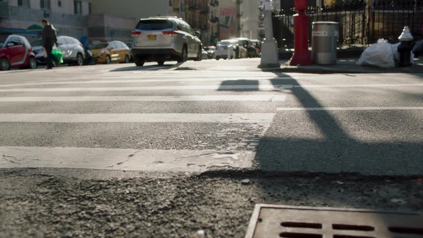 A shot of a crosswalk in an urban environment with people and traffic in the background