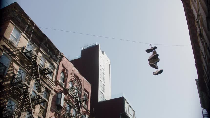 Strung together shoes hang on a cable between apartment buildings