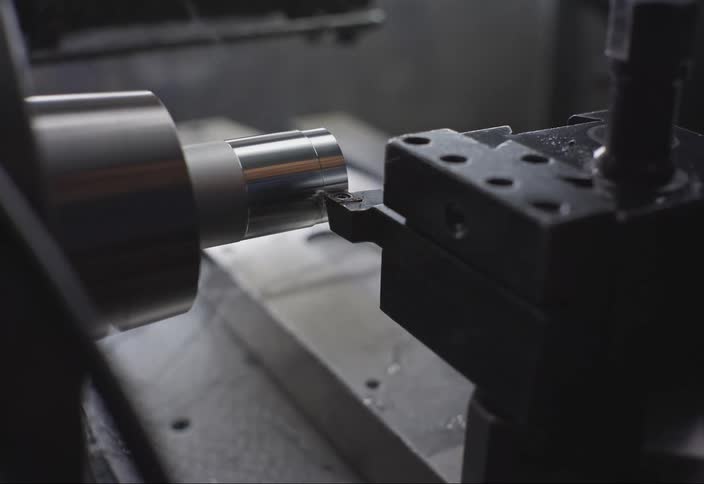 A spinning part of a machine shaves chips off of a piece of metal