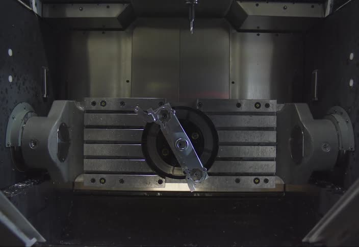 Interior of a cnc machine with a metal part attached to the rotating shaft and a cutting tool positioned above