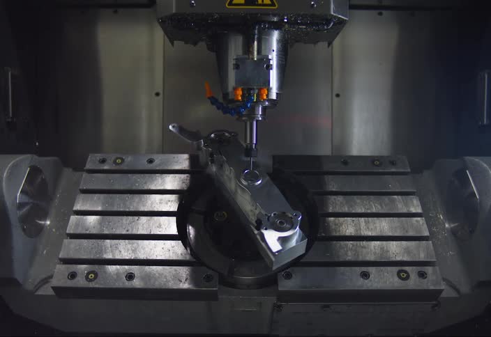 Large machine base tilts metal object while drill operates on the object