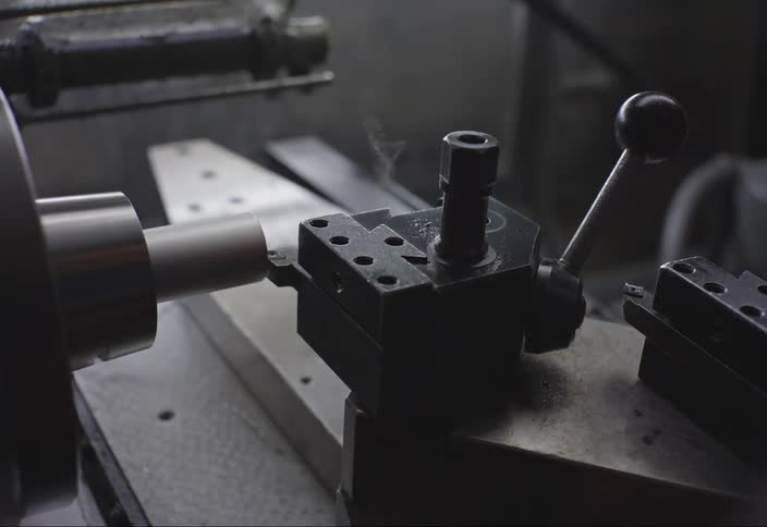 A machine mills a small piece of metal in a factory
