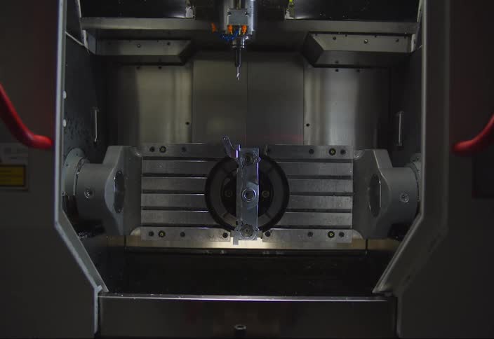 A metal door opening and inside there is an industrial machine drilling into an object that is rotating
