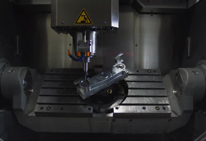 Closeup of a cnc machine in operation with a metal part clamped and the cutting tool in action
