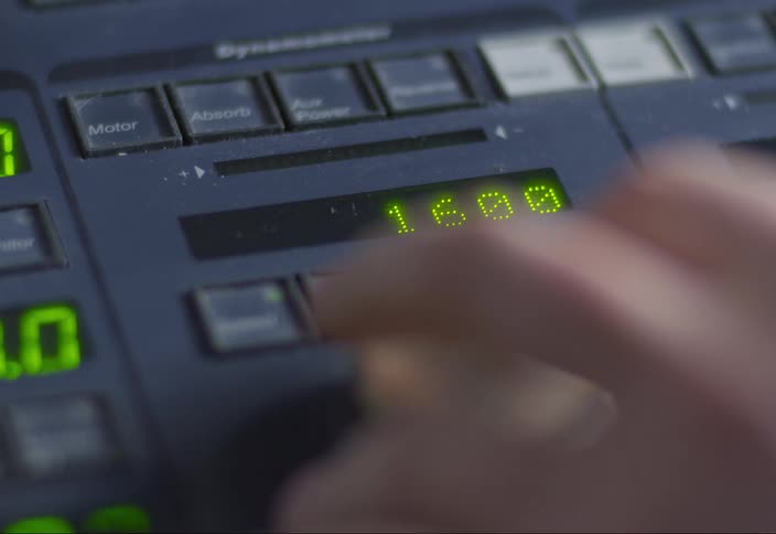 A mans hand spins a dial on a machine to make numbers go up on a display