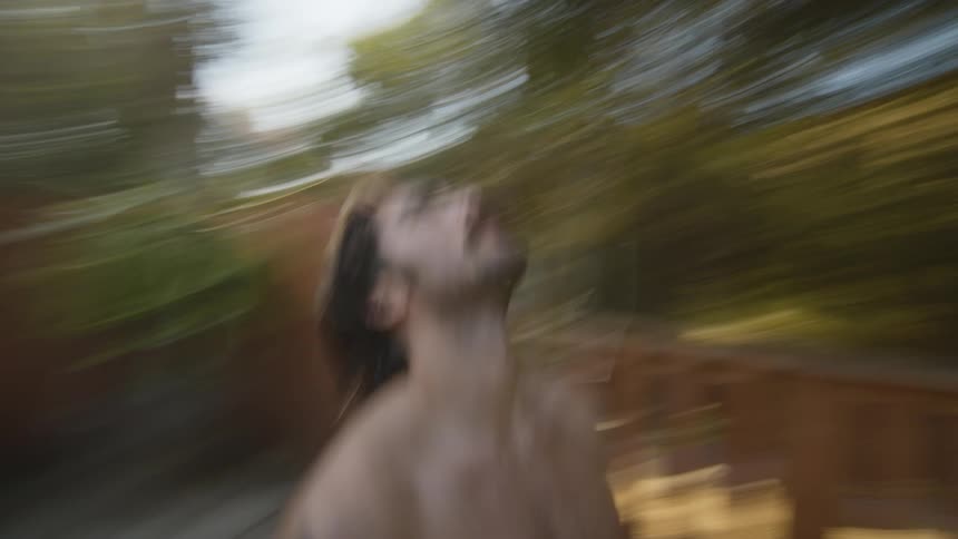 A strong shirtless muscular young man stands looking up in the backyard in the morning