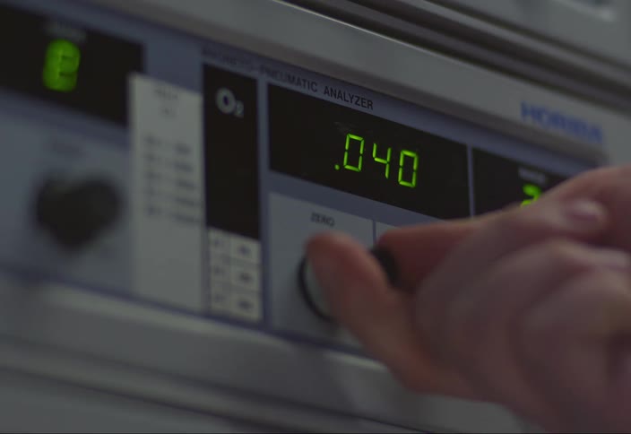 Closeup of a hand adjusting a dial on electronic equipment with digital displays