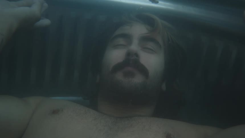 Man holding his breath while diving into a tub of water and coming back to the surface and releasing his breath