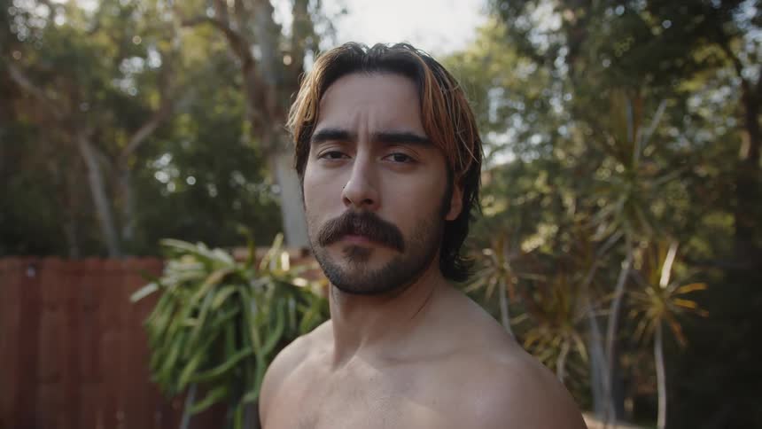 Portrait of a shirtless man with a beard stretching his neck