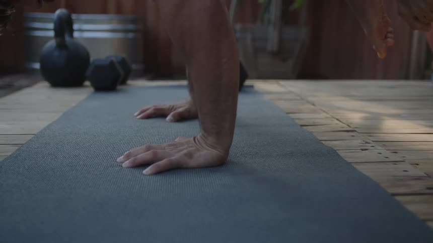 Man carefully lifts his legs in order to balance on his arms while exercising