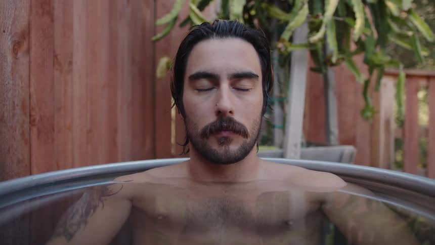 Portrait of a man relaxing and concentrating inside a basin of water with his body submerged