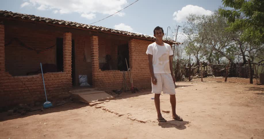 Man standing next to a precarious house on a farm