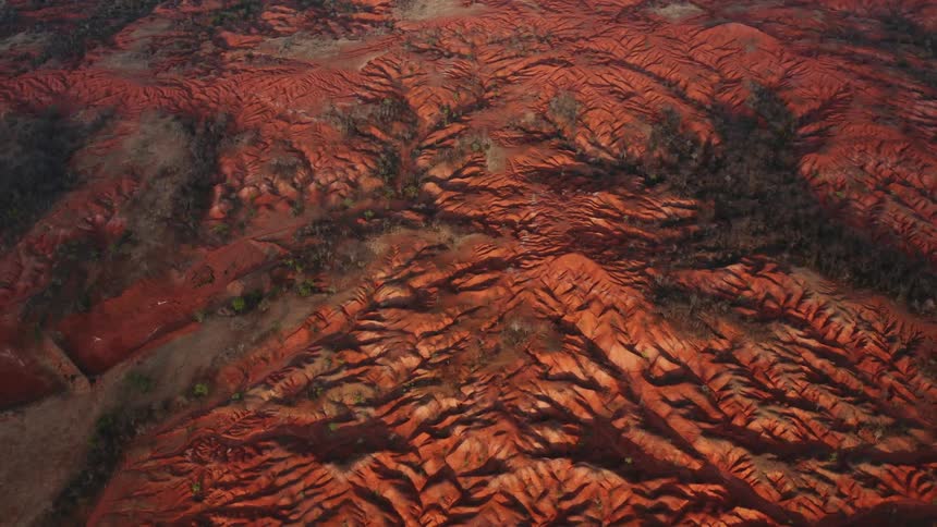 Groves and woods dot small valleys in red mountainous terrain
