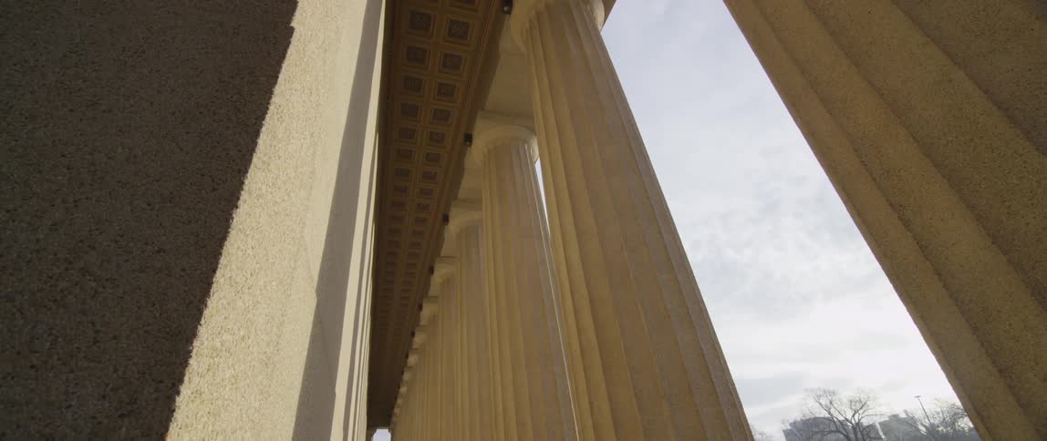White marble pillars against a cloudy sky